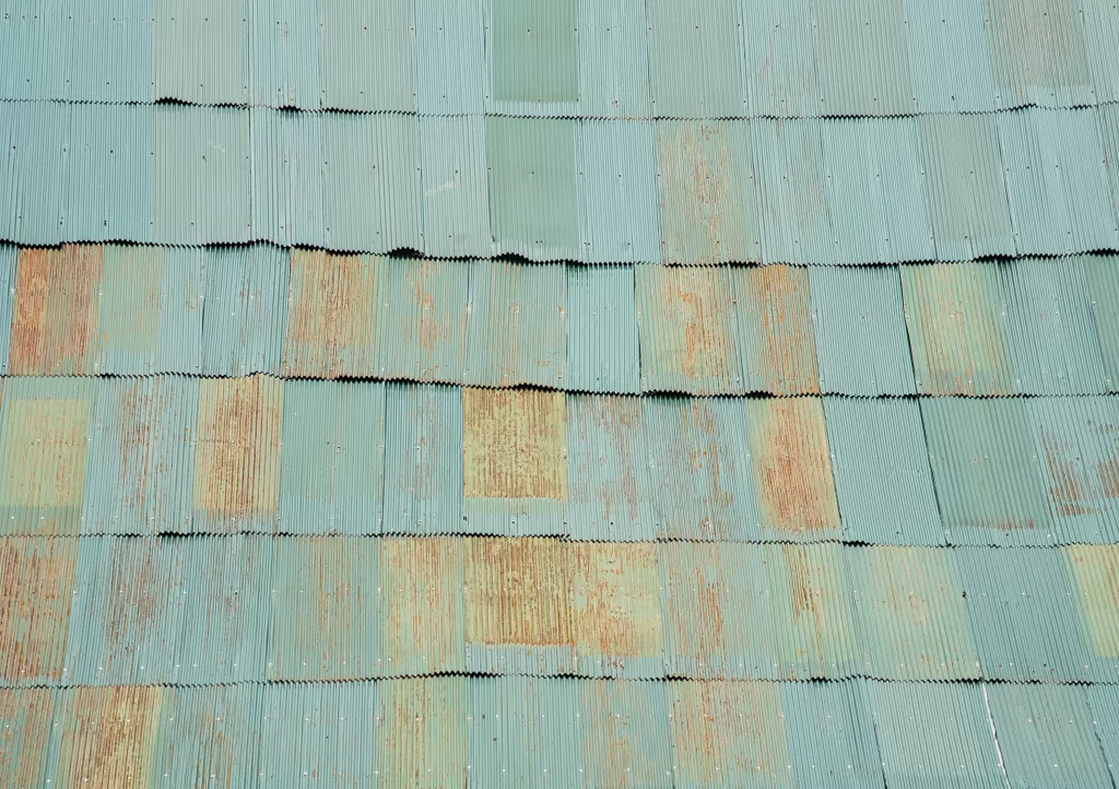 Corrugated metal roof panels in shades of green with patches of rust and wear.