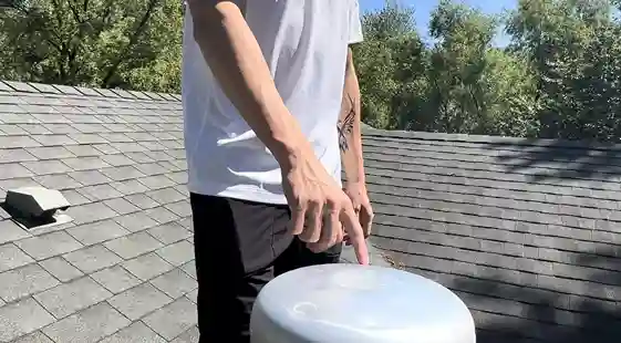 Man pointing at storm damage on a roof vent.