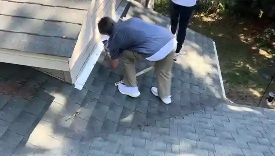 Man photographing roof damage with a ruler in hand.