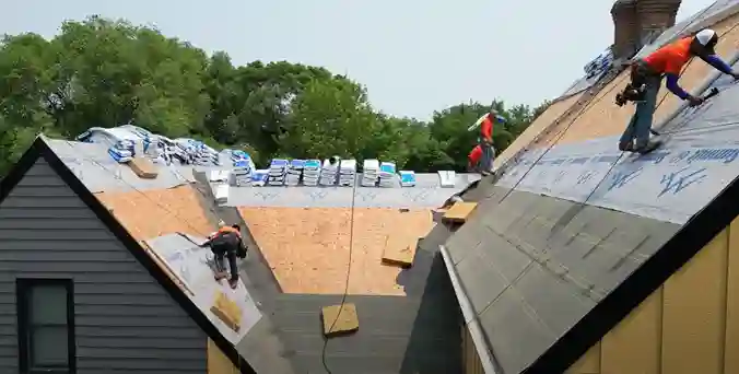 3 roofers with orange shirts on a roof.