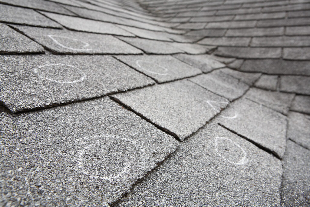 Close up of a roof with chalk marks indicating storm damage.