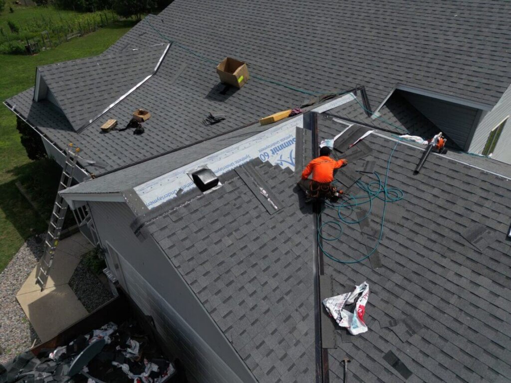 Men replacing a roof with orange shirts