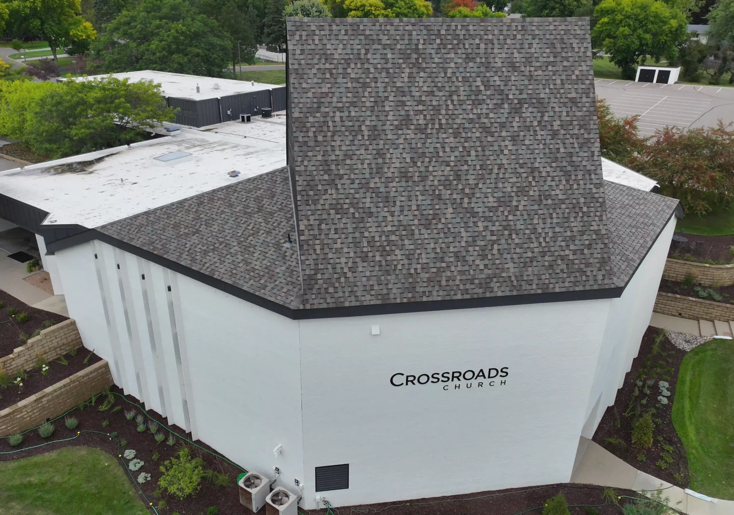 Arial view of Crossroads Church, a large white building with a mix of brown shingles