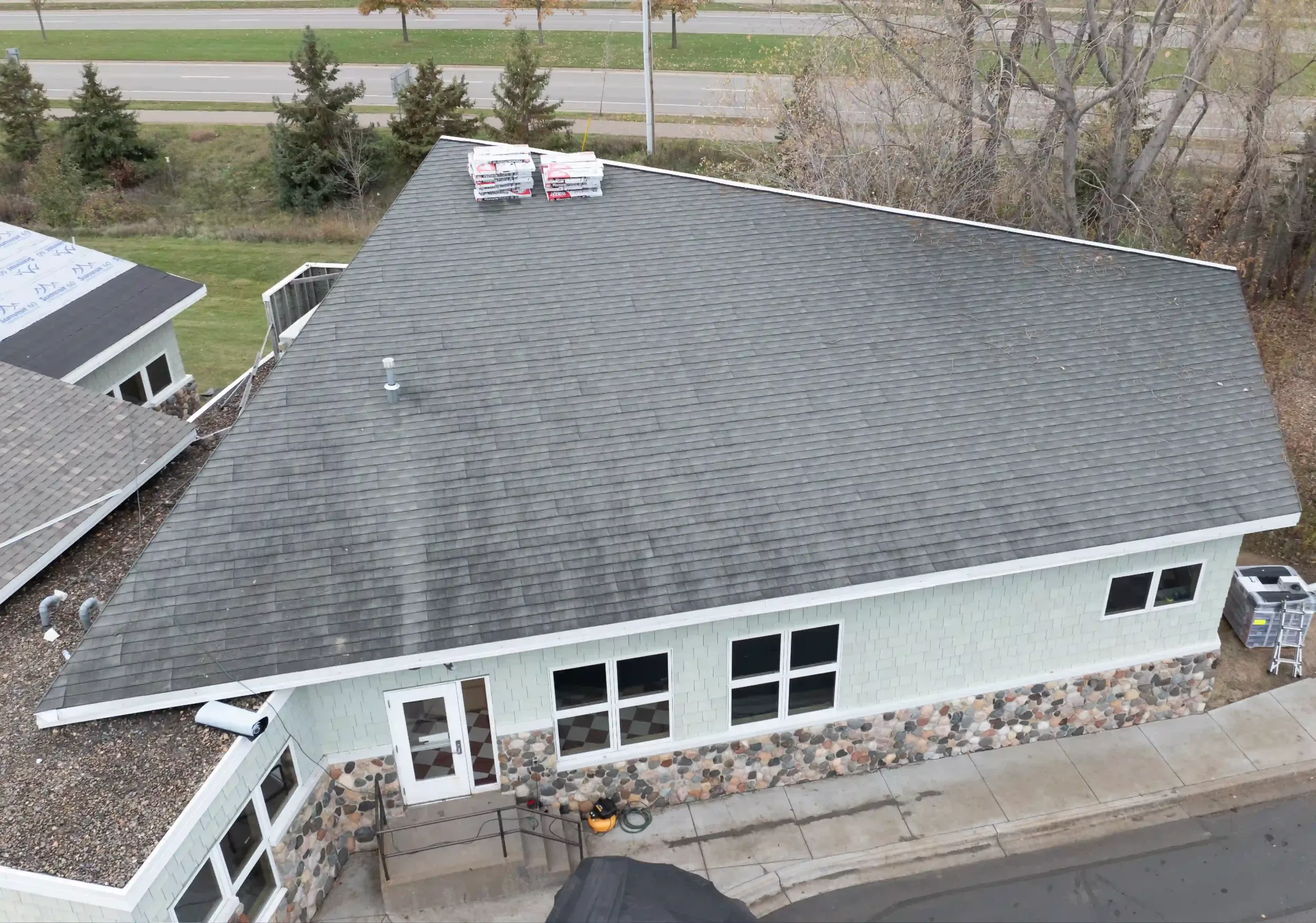 Faded gray roof shingles in need of replacement on light blue residential building.